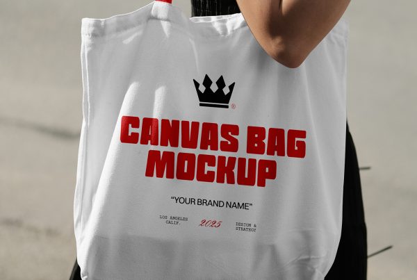 Front view of a white canvas bag mockup with a red handle worn by a woman on the streets.
