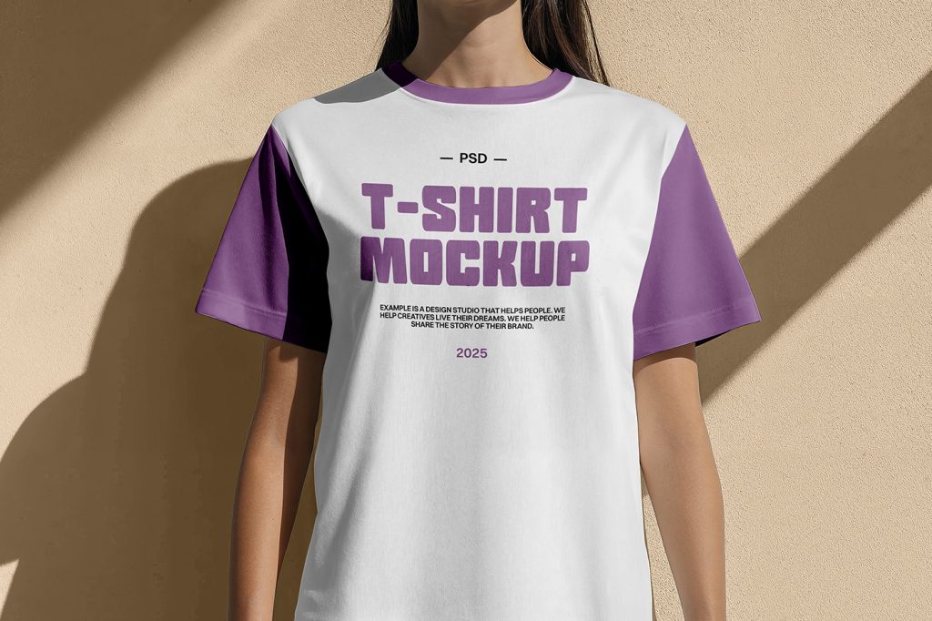 Front view white and purple T-shirt mockup worn by women and standing in front of the beige wall color.