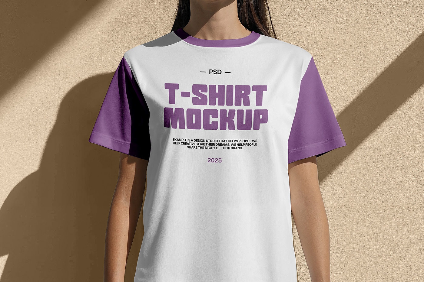Front view white and purple T-shirt mockup worn by women and standing in front of the beige wall color.