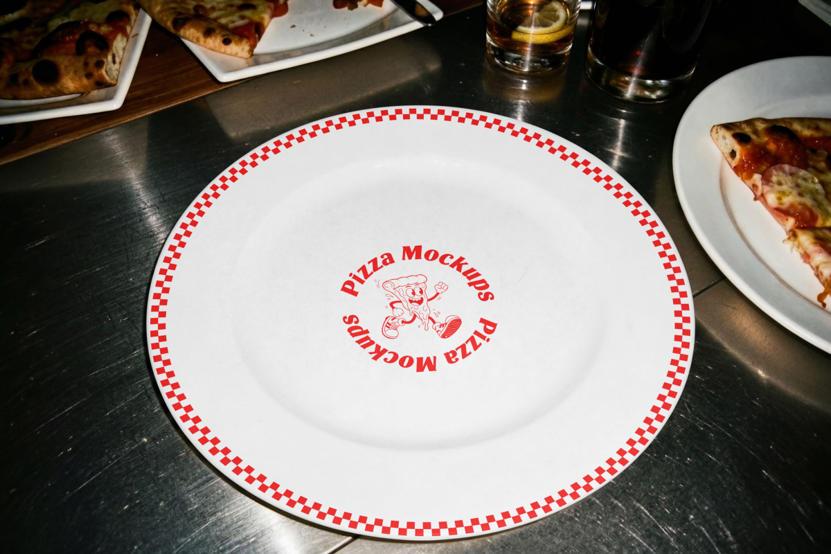 A white ceramic plate with a red checkered border. In the center, there is a red circular logo with the text Pizza Mockups and a cartoon illustration of a running pizza slice.