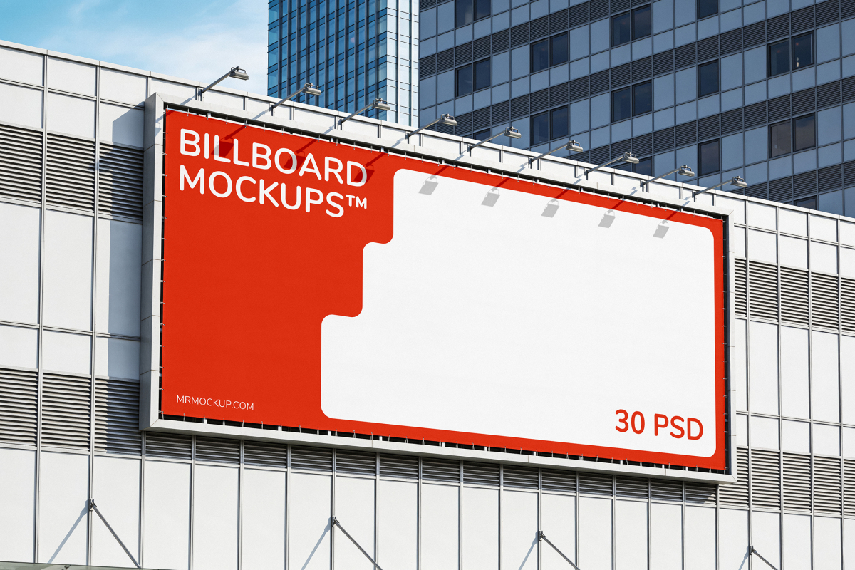 Wide horizontal billboard with overhead lights mounted on a modern building facade with light metal paneling.