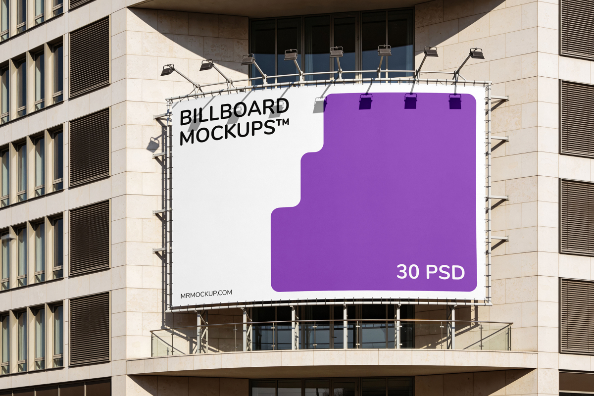 Large horizontal outdoor billboard mounted on the stone facade of a modern building, fitted with overhead spotlights.