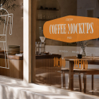 A coffee shop window displaying custom decals, including a white Moka pot illustration, an orange badge reading "Fresh Coffee Mockups PSD", and opening hours "10:00 - 19:00" on the glass.