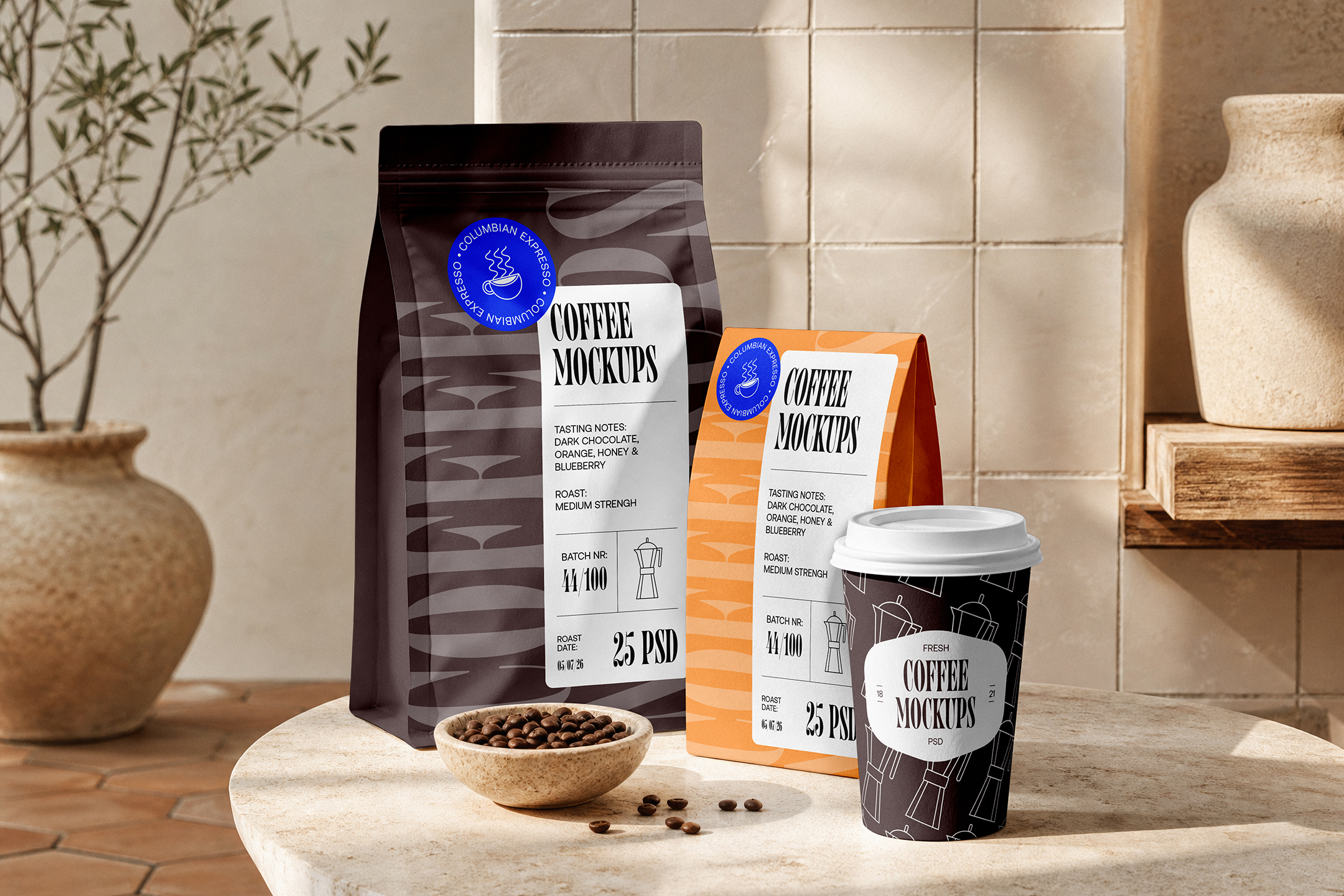 Coffee-Branding-Mockups-02-CMV2-A A set of coffee packaging mockups on a stone counter, featuring a dark brown coffee bag, an orange bag, a patterned paper cup, and a small bowl of roasted coffee beans.