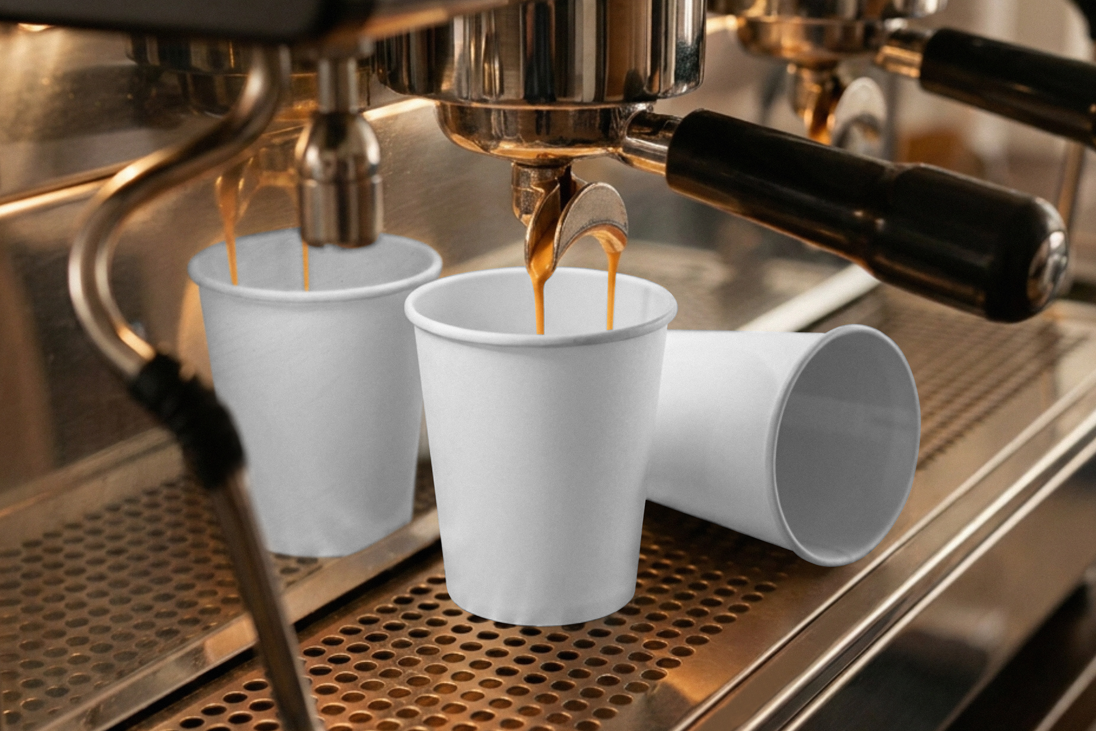 Fresh espresso pouring from a coffee machine group head into a blank white paper cup on a stainless steel drip tray.