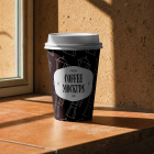 A dark brown paper coffee cup with a white lid resting on a terracotta tiled windowsill under warm sunlight and foliage shadows.