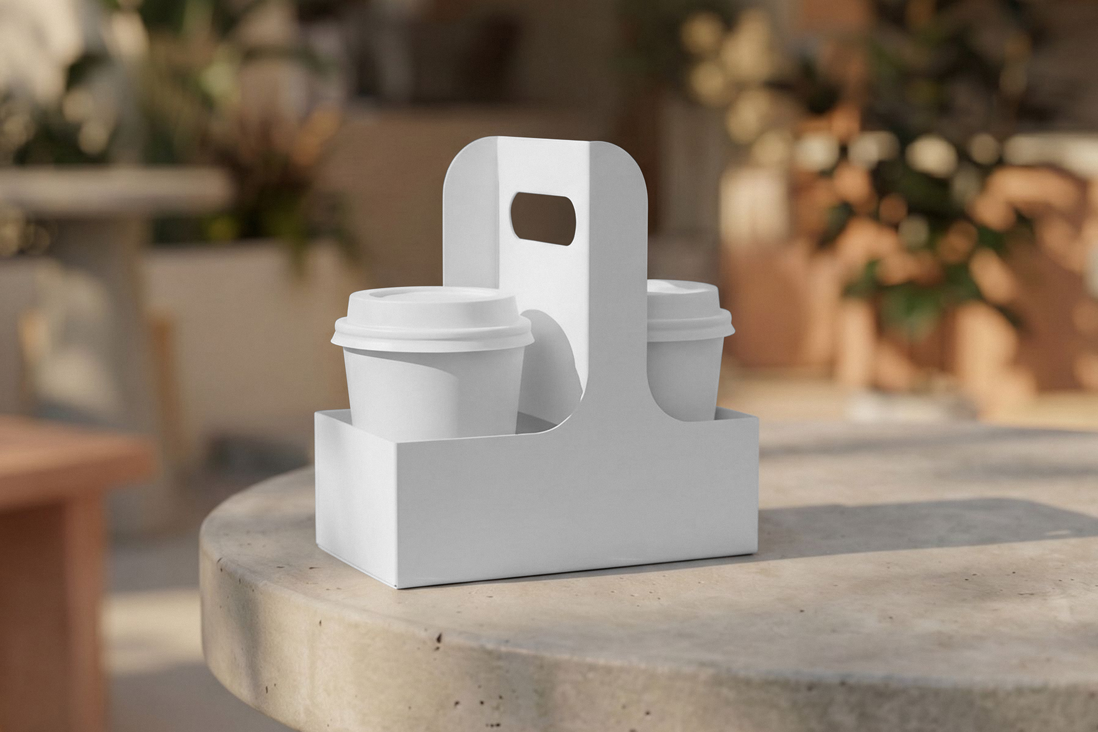 Two white paper takeaway coffee cups with lids inside a blank white cardboard cup holder carrier on a round stone table outdoors.