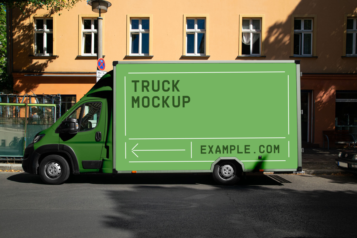 Side view of a green commercial box truck mockup parked on an urban street in front of a yellow residential building.