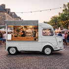 Vintage white Citroen HY coffee truck mockup with open hatch at a crowded evening street festival.