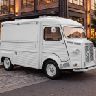 Vintage white Citroen HY food truck mockup with closed hatch parked on a paved street in front of brick buildings during evening.