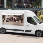 White van food truck mockup with open hatch and chef working inside, parked outside a modern office building.