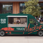 Side view of a dark green burger food truck mockup with an open service hatch and a chef preparing food inside, parked next to an outdoor cafe seating area.