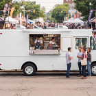 White step van food truck mockup with open hatch and customers chatting in front at a lively outdoor festival.