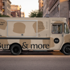 Profile view of a beige food truck mockup with a closed service window, parked along a city street curb during golden hour.