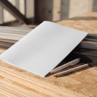 Blank white folder mockup placed on stacked OSB boards next to metal profiles and pens.