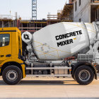 Side view of a yellow concrete mixer truck with a white branded drum parked at a construction site.