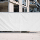 Large blank white vinyl banner mounted on a temporary metal construction site fence.
