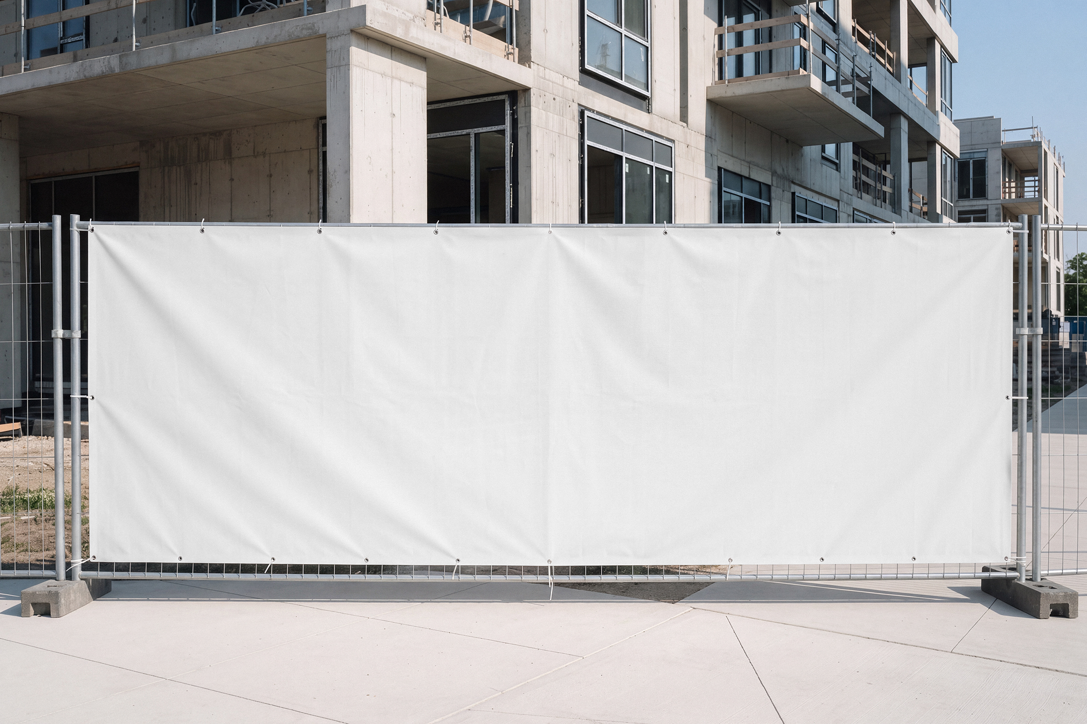 Large blank white vinyl banner mounted on a temporary metal construction site fence.