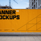 Large horizontal yellow promotional banner mounted on a wire fence around a construction site.