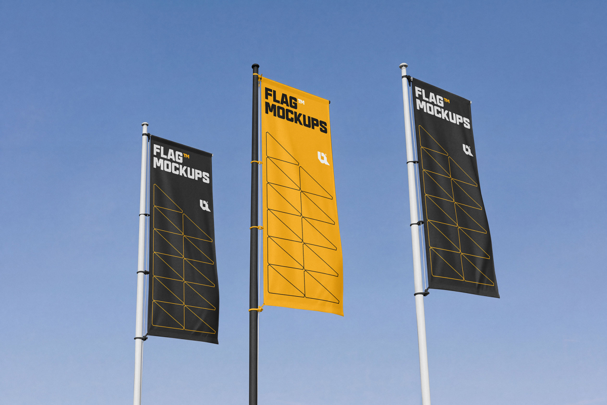 Three vertical flag banners in black and yellow were hoisted on flagpoles against a clear blue sky.
