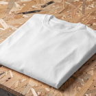 A folded plain white t-shirt lying on a wooden OSB board surface.