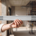 Close-up of a hand holding a folded white wooden meter ruler at an indoor construction site.