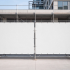 Blank white mesh scaffold banners mounted on a metal construction barrier.