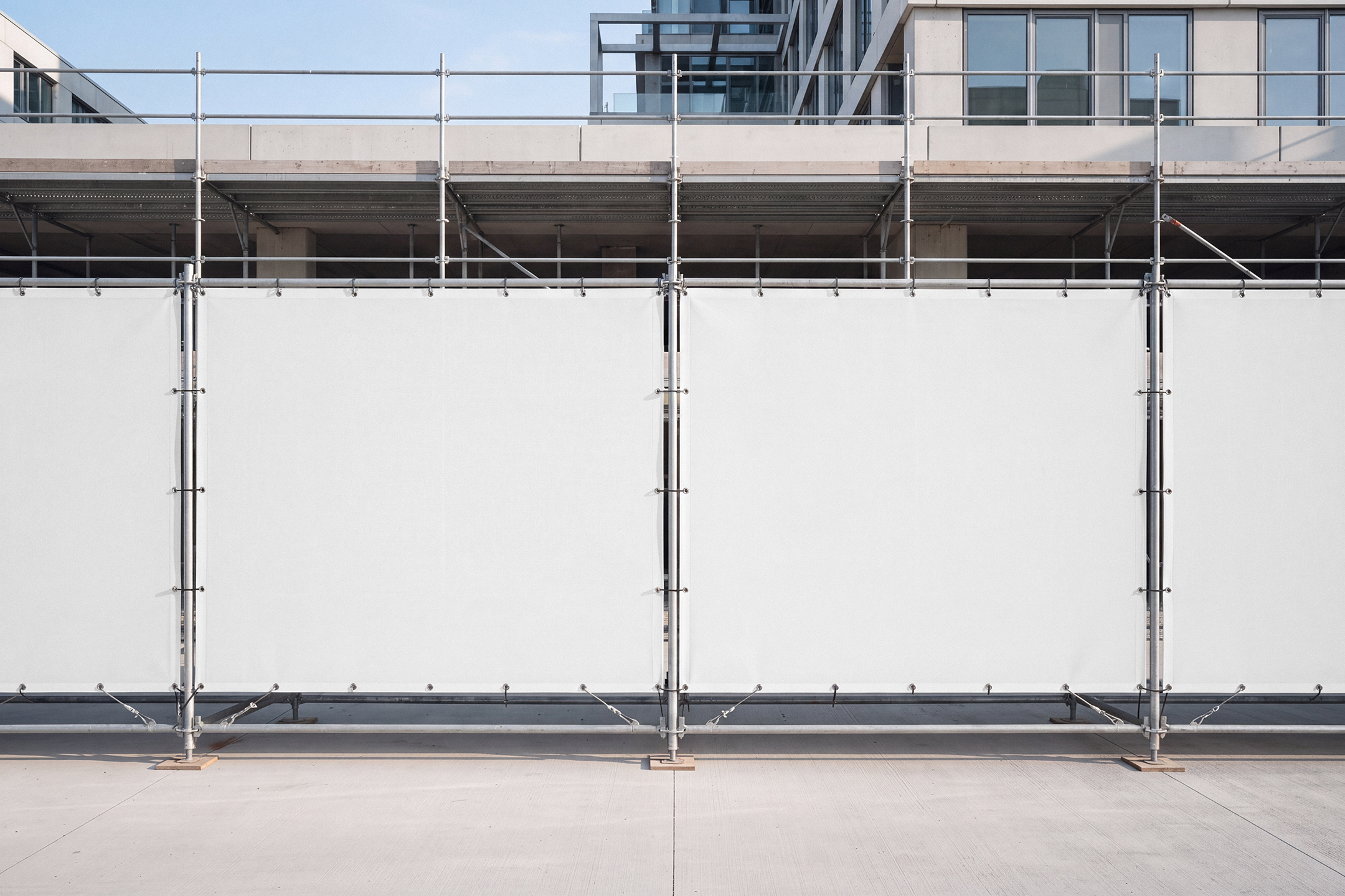 Blank white mesh scaffold banners mounted on a metal construction barrier.