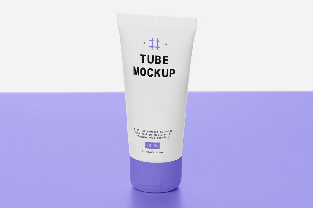 A front-view shot of a blank white plastic cosmetic tube template standing vertically on its cap against a minimal, bright white background. Designed as a PSD packaging mockup for cream, lotion, or skincare products, featuring subtle reflections and realistic shadows on a smooth table surface. Free Cosmetic Tube on Table Mockup