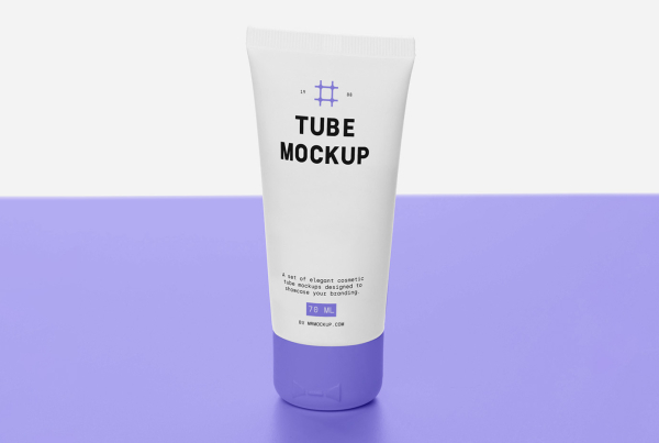 A front-view shot of a blank white plastic cosmetic tube template standing vertically on its cap against a minimal, bright white background. Designed as a PSD packaging mockup for cream, lotion, or skincare products, featuring subtle reflections and realistic shadows on a smooth table surface. Free Cosmetic Tube on Table Mockup