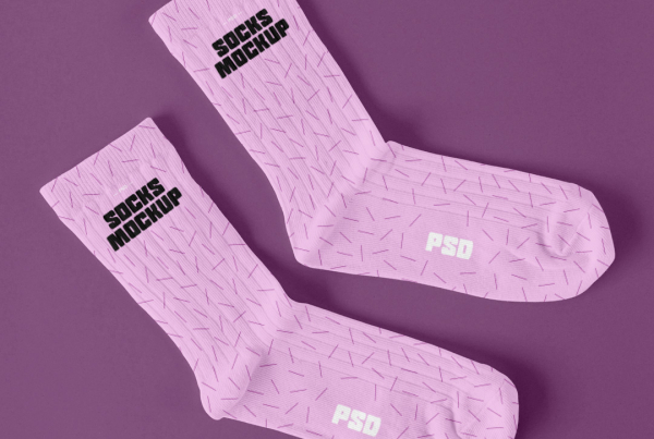 A high-angle flat lay mockup featuring a pair of blank white crew socks made of ribbed cotton knit fabric, placed side-by-side on a seamless, light off-white background with soft, natural shadows. Free Laying Pair of Socks Mockup