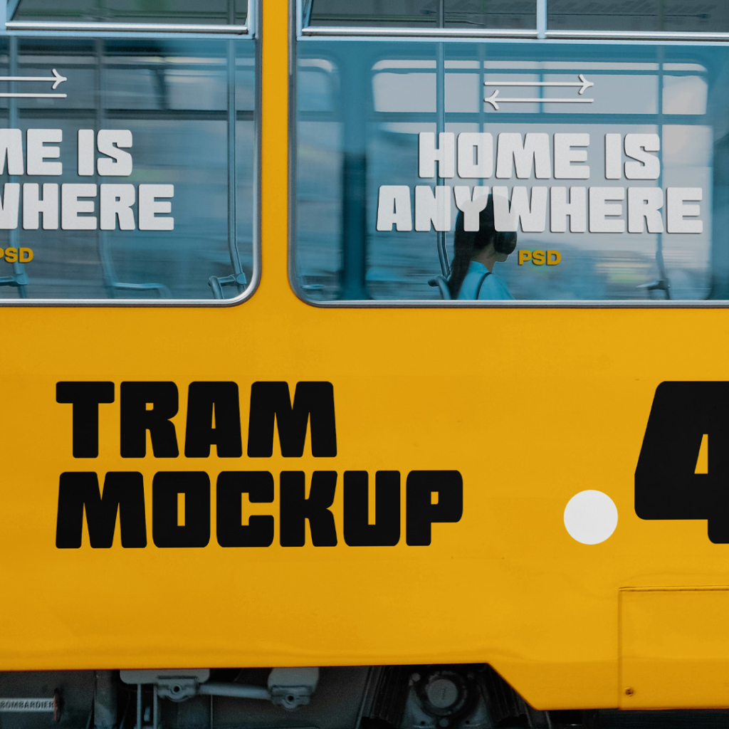 A side-view close-up shot of a modern white city tram featuring large glass windows, white folding doors, and a blank side panel ideal for advertising mockups. Inside the tram, a passenger wearing headphones is visible looking out the window. Free Tram Side View Mockup