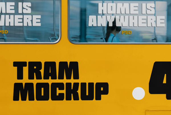 A side-view close-up shot of a modern white city tram featuring large glass windows, white folding doors, and a blank side panel ideal for advertising mockups. Inside the tram, a passenger wearing headphones is visible looking out the window. Free Tram Side View Mockup