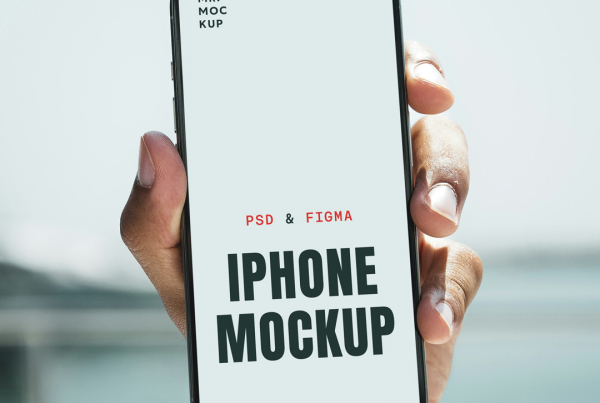 A close-up shot of a person's hand holding a modern iPhone Pro vertically toward the camera, featuring a blank white screen with a Dynamic Island display notch. The background shows a soft-focus, bright outdoor setting with a blurred view of a water feature and a man wearing sunglasses partially visible on the left. Free iPhone Pro Scene PSD Mockup