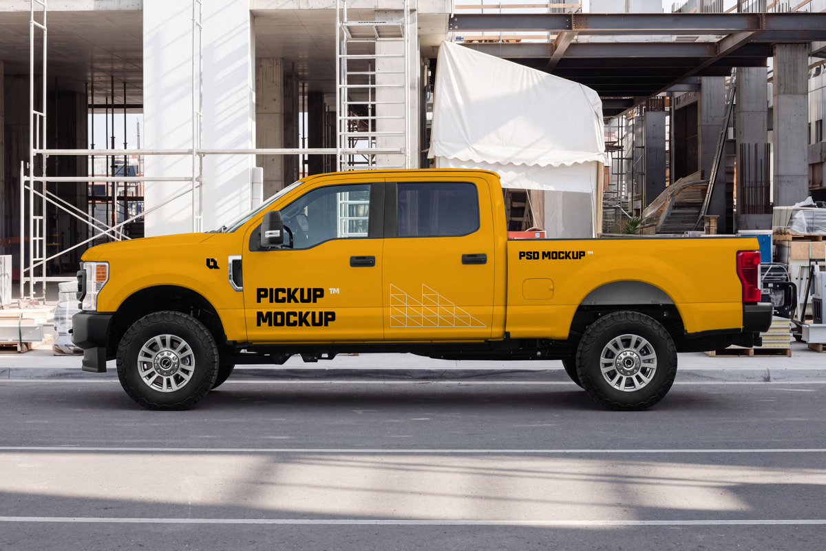 Side profile of a yellow crew-cab pickup truck parked near a construction site structure.