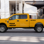 Side profile of a yellow crew-cab pickup truck parked near a construction site structure.