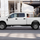 Side view of a white crew cab pickup truck parked alongside a construction site.