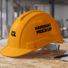 A yellow safety hard hat resting on a wooden workbench next to blueprints and a pen.