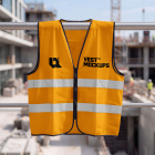 High-visibility yellow safety vest with reflective stripes hanging on a metal railing at a construction site.