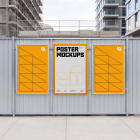 Three framed yellow and white promotional posters mounted on a metal construction site fence.