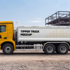Side view of a yellow heavy-duty tipper truck with a white cargo box at an active construction site.