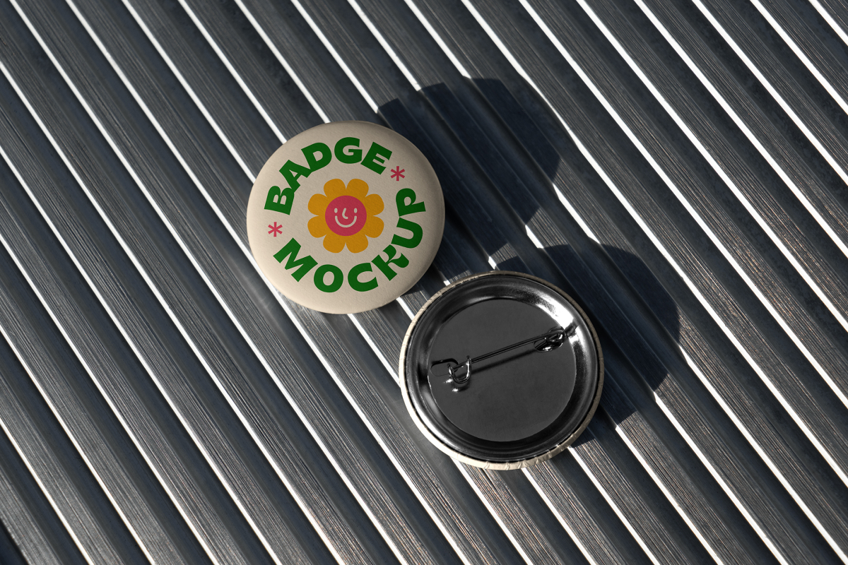 Pair of round button badges on a metallic ribbed background, highlighting the front graphic surface and the sturdy metal back pin attachment.