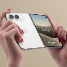Hands holding a silver partially folded smartphone from the back, showing the white rear case, camera module, and screen displaying a desert landscape.