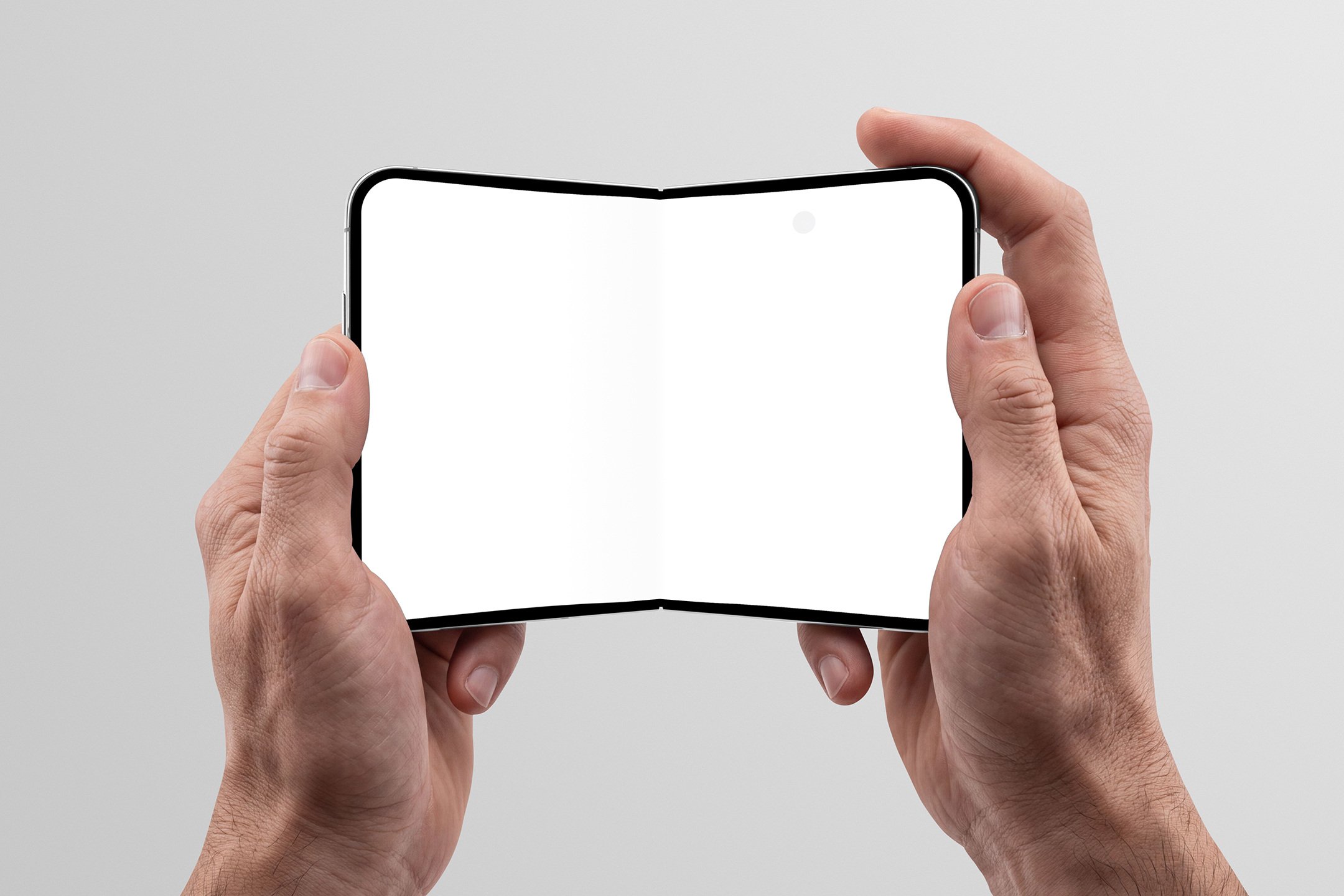 Two hands holding an open foldable smartphone with a blank white inner display against a light gray studio background.
