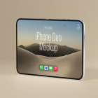 Three-quarter perspective view of an unfolded silver foldable smartphone standing upright on a beige background, showing a desert landscape display.