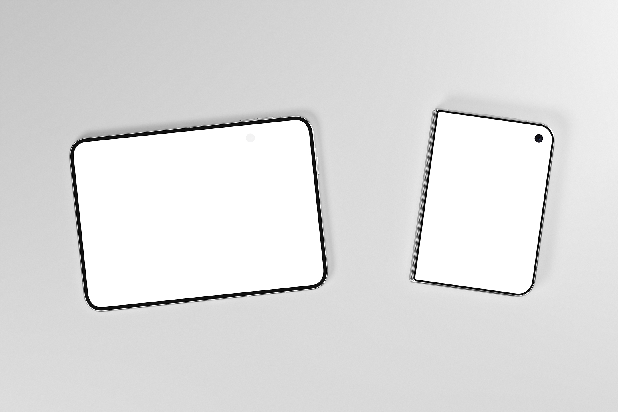 Top-down view of two foldable smartphones lying on a gray surface, one fully open and one folded with blank white screens.