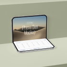 Front perspective view of a partially folded silver smartphone standing open on a green display shelf, showing a desert wallpaper on top and a calendar interface below.